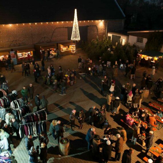 Schumacher Weihnachtsmarkt von oben, mit schöner Weihnachtsbeleuchtung und Tischen und Bänken zum Sitzen sowie Verkaufsstände im Innenhof